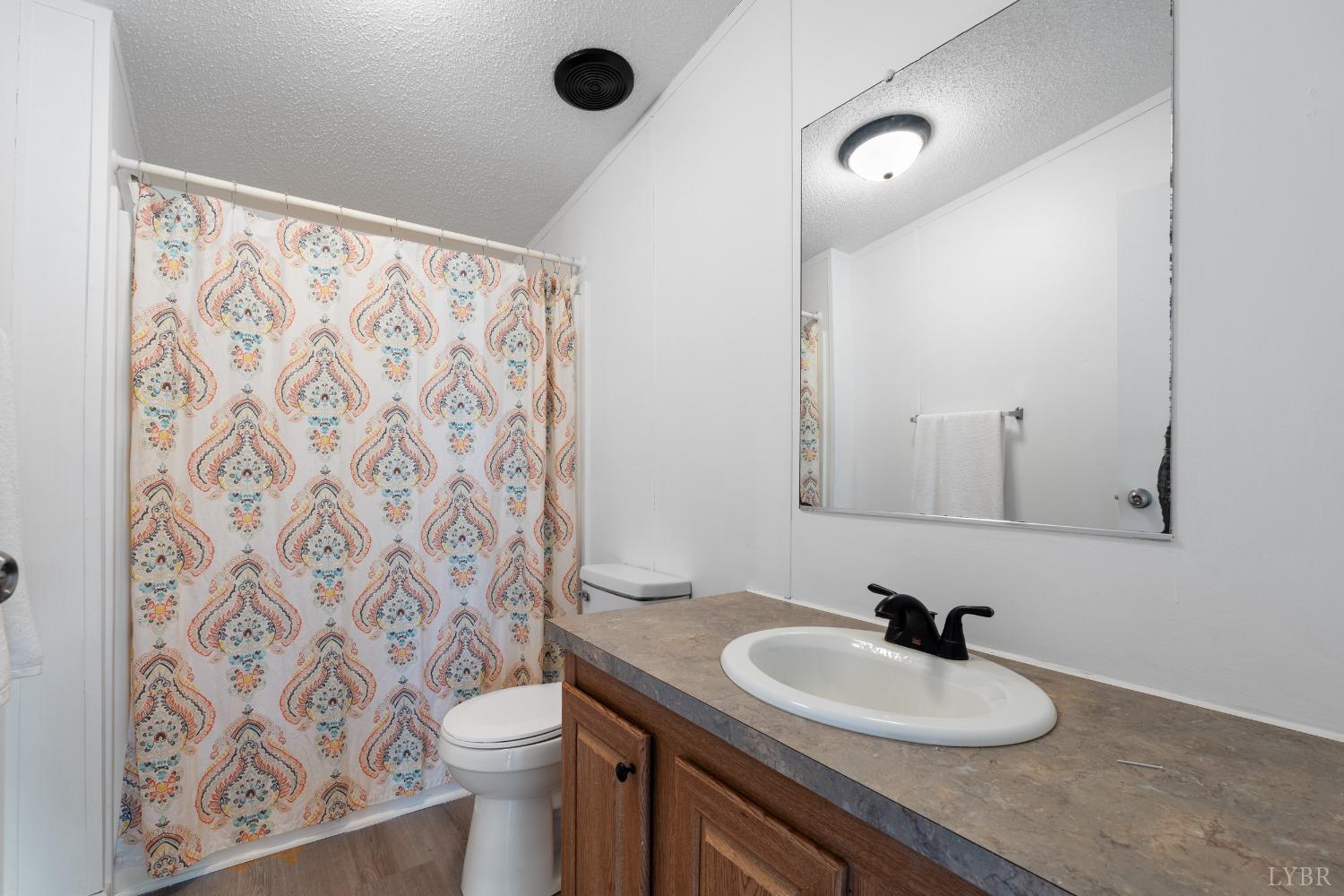 128 Douglas Drive Dry Fork, VA 24549 - Photo 26 of 45 a bathroom with a granite countertop sink a toilet and a shower curtain