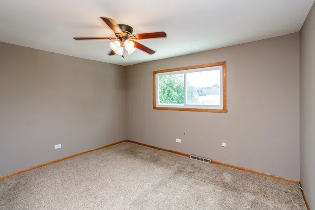 an empty room with a ceiling fan and window