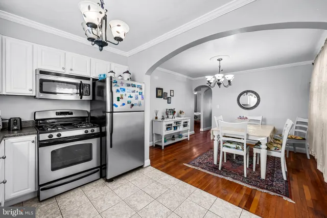 a view of a kitchen with stainless steel appliances granite countertop a stove top oven a chimney cabinets and a dining table