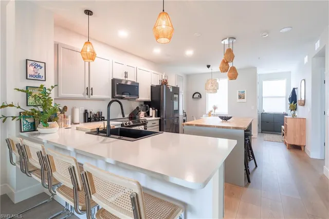 a kitchen with kitchen island a stove a chandelier a dining table and chairs with wooden floor