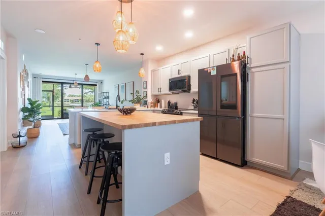 a kitchen with stainless steel appliances a refrigerator a sink dishwasher a dining table and chairs with wooden floor