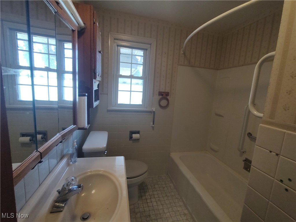 5704 Middle Ridge Road Madison, OH 44057 - Photo 25 of 50 Bathroom with shower / bathtub combination, toilet, a sink, tile patterned flooring, and wallpapered walls