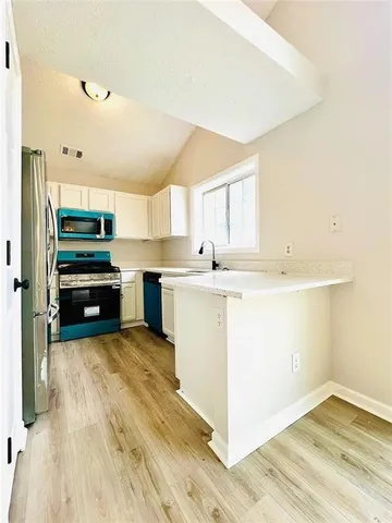 a kitchen with a sink cabinets appliances and a window