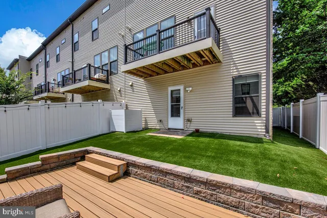 a view of a backyard with plants and white fence