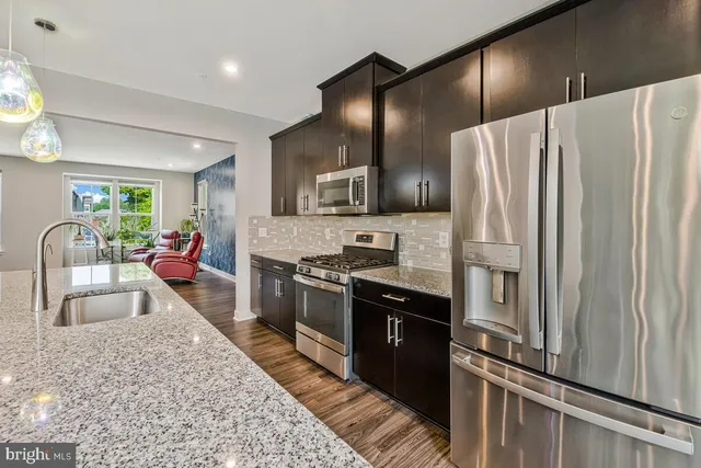 a kitchen with stainless steel appliances granite countertop a sink and a refrigerator