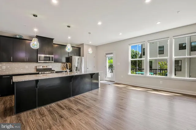 a kitchen with stainless steel appliances kitchen island granite countertop a refrigerator and a sink