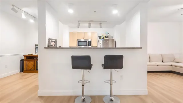 a kitchen with stainless steel appliances granite countertop a sink a stove a refrigerator a microwave oven with white cabinets and wooden floor