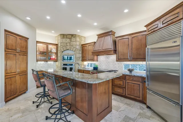a kitchen with stainless steel appliances granite countertop a table chairs sink refrigerator and cabinets