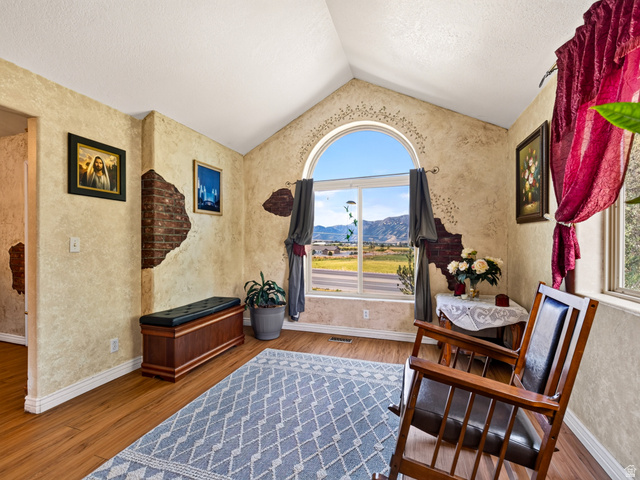4380 Main Street Logan, UT 84321 - Photo 14 of 74 Front entry living room with vaulted ceiling, LVP flooring, arched window, textured walls, and faux exposed brick accents