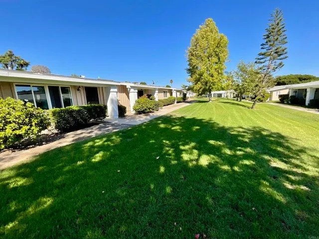 a front view of house with yard and trees in the background