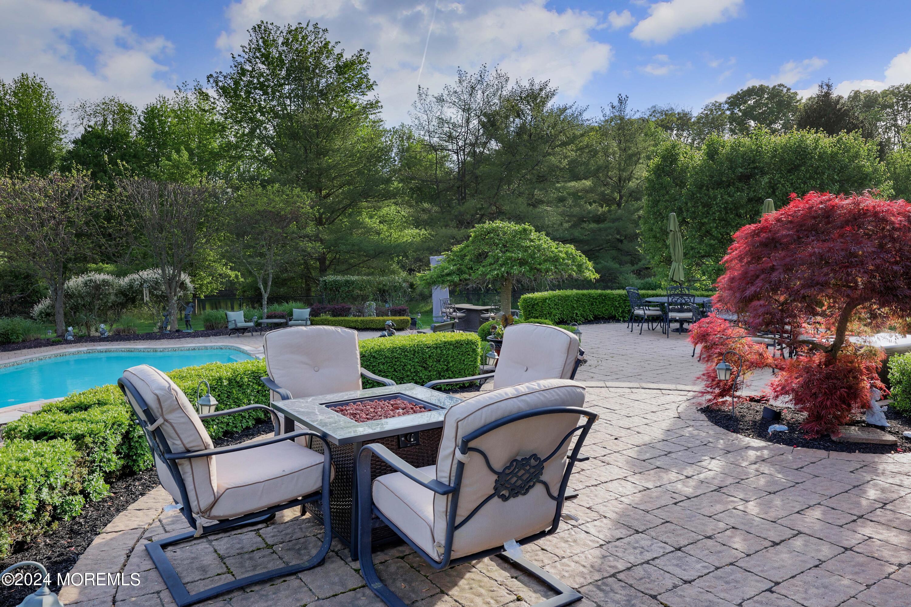 12 Shadowbrook Drive Colts Neck, NJ 07722 - Photo 25 of 33 a view of a patio with couches chairs and a fire pit and an umbrella