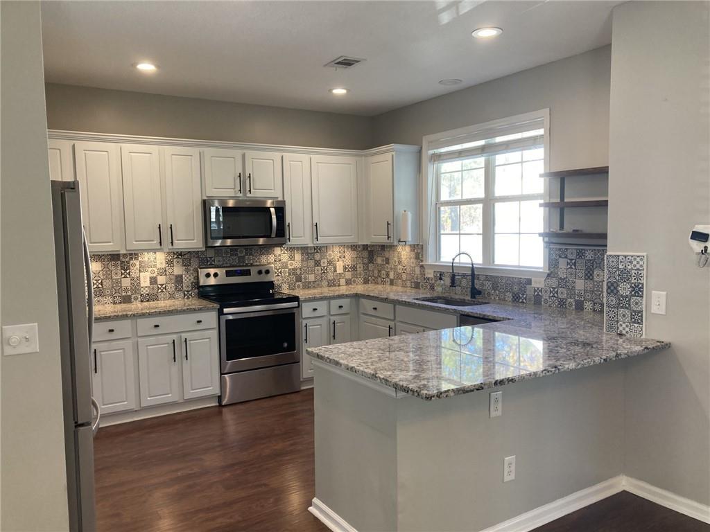 66 Godley Park Way Savannah, GA 31407 - Photo 2 of 20 a kitchen with kitchen island granite countertop a stove a sink and a granite counter tops with wooden floors