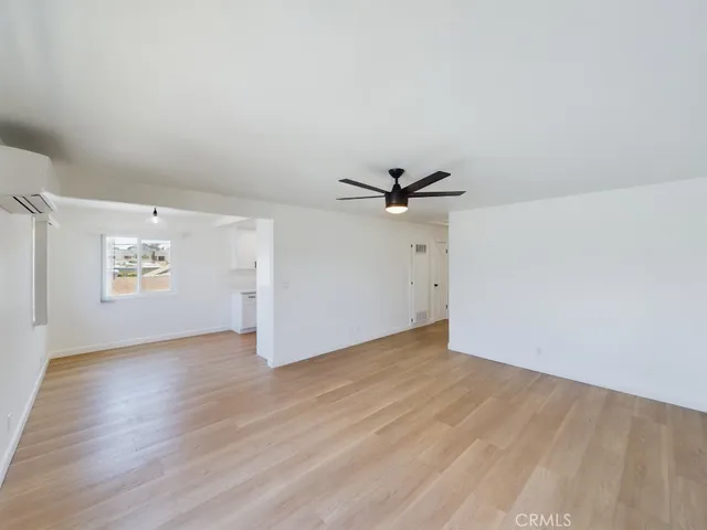 an empty room with wooden floor closet and windows