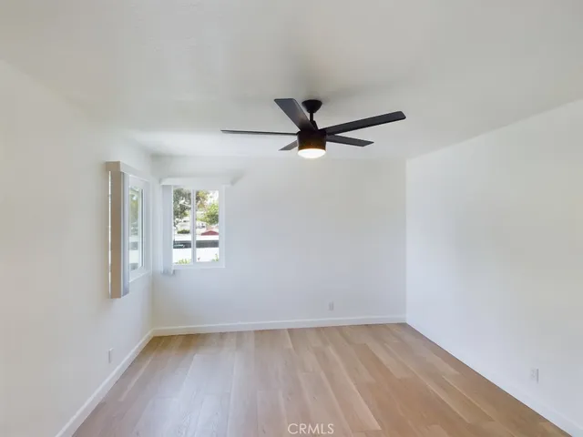 an empty room with windows and ceiling fan
