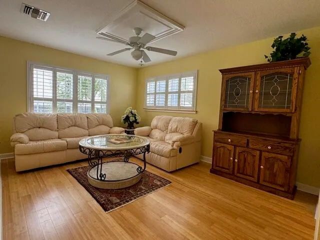 a living room with furniture a ceiling fan and a flat screen tv