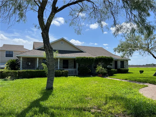 a front view of a house with a yard and tree