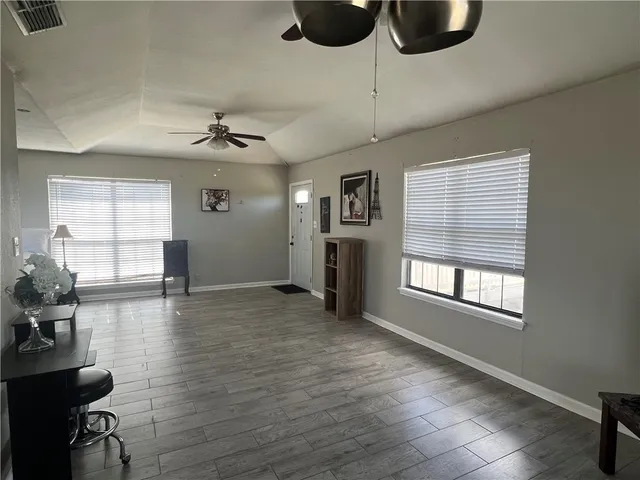 a view of an empty room with a window and wooden floor