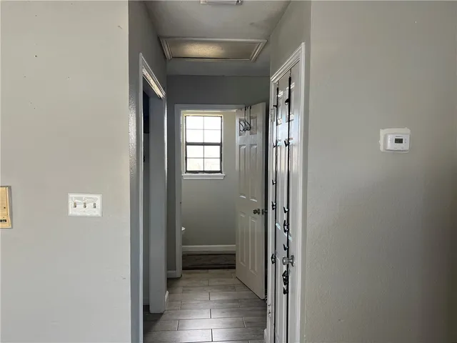 a view of a hallway with wooden floor and a bathroom