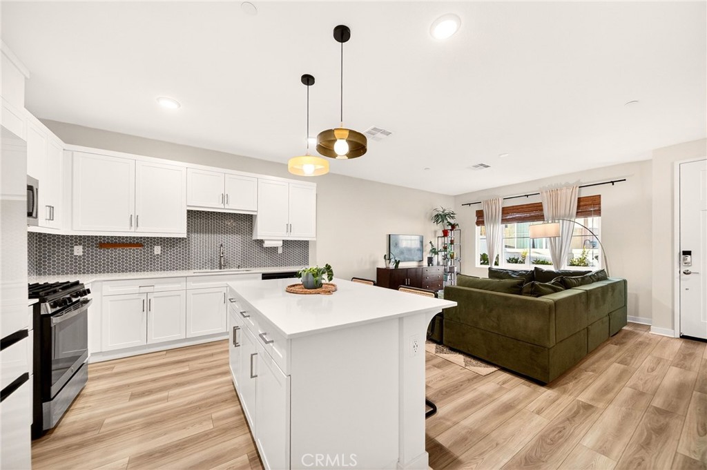 35165 Rangpur Lane Fallbrook, CA 92028 - Photo 8 of 42 a kitchen with a stove a refrigerator and white cabinets with wooden floor