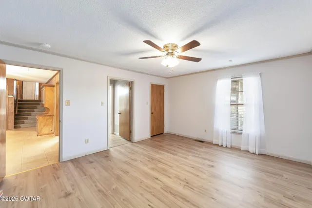 an empty room with wooden floor and a ceiling fan