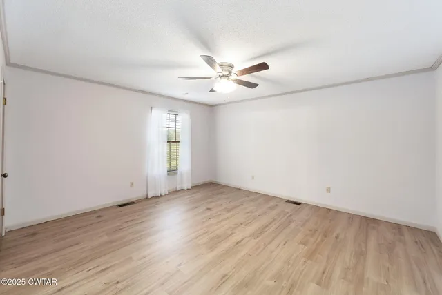 an empty room with wooden floor and ceiling fan