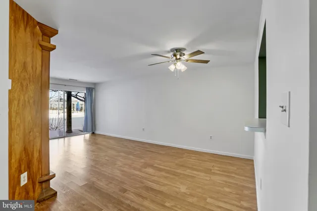 a view of an empty room with a window and wooden floor