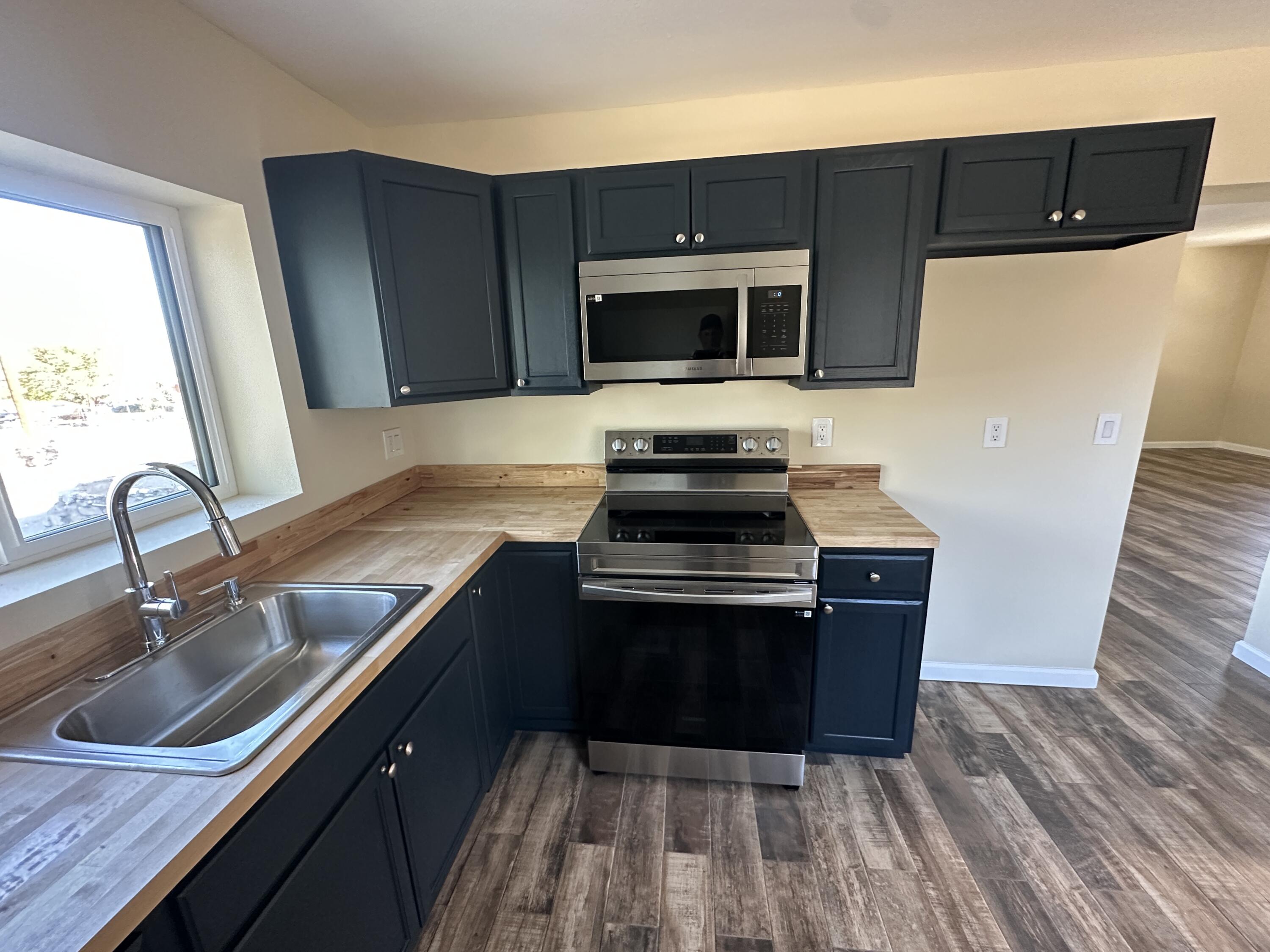 12164 B Street Trona, CA 93562 - Photo 9 of 41 a kitchen with stainless steel appliances a sink a stove a microwave and wooden cabinets