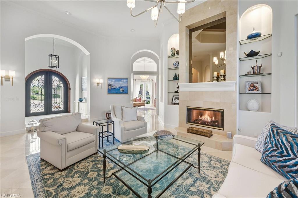 Living area with built in shelves, ornamental molding, a tile fireplace, a chandelier, and french doors
