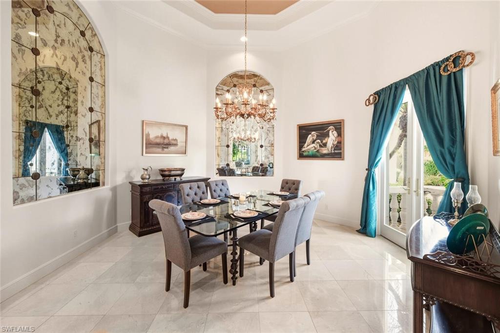 396 Terracina Way Naples, FL 34119 - Photo 12 of 50 Dining area featuring ornamental molding, a chandelier, a high ceiling, and a tray ceiling