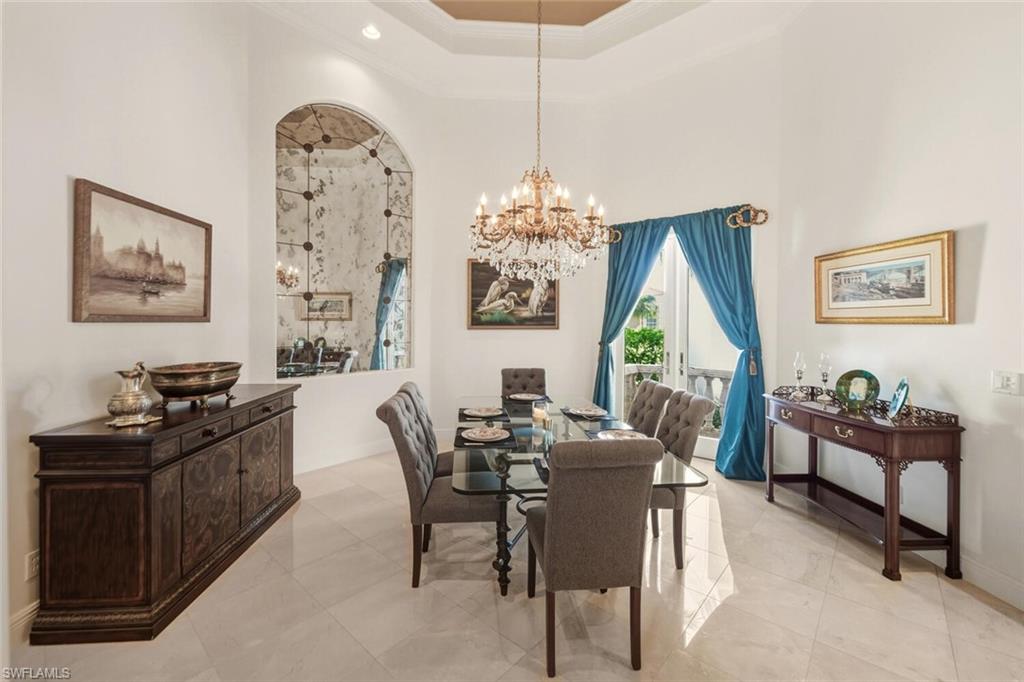 396 Terracina Way Naples, FL 34119 - Photo 13 of 50 Dining space with ornamental molding, a towering ceiling, a chandelier, and a raised ceiling