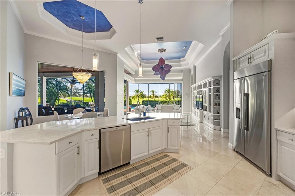 396 Terracina Way Naples, FL 34119 - Photo 20 of 50 Kitchen with a tray ceiling, stainless steel appliances, decorative light fixtures, light stone countertops, and white cabinets
