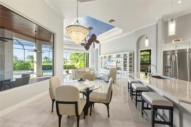 a view of a dining room with furniture a chandelier and large windows