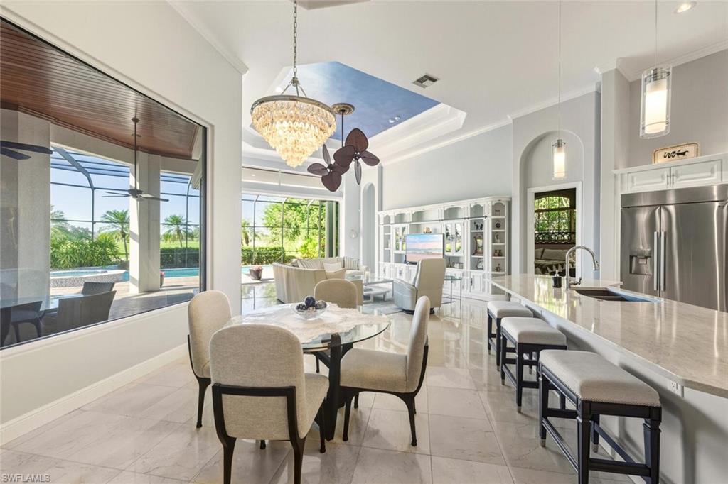 396 Terracina Way Naples, FL 34119 - Photo 22 of 50 Dining space with crown molding, a sunroom, arched walkways, a raised ceiling, and a high ceiling