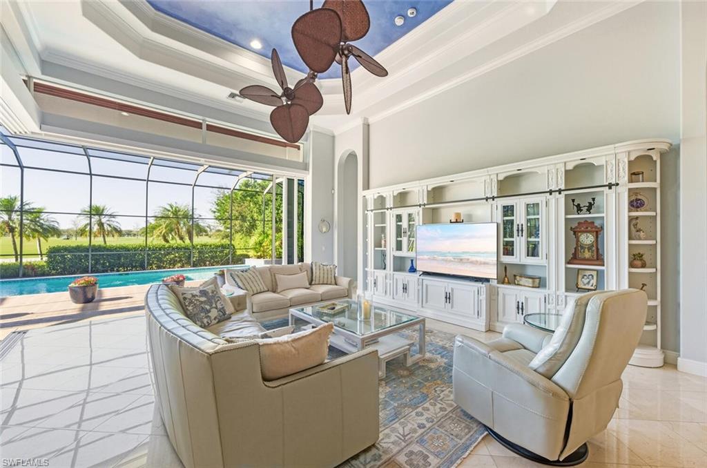 396 Terracina Way Naples, FL 34119 - Photo 23 of 50 Living room featuring a sunroom, a tray ceiling, a high ceiling, a ceiling fan, and ornamental molding