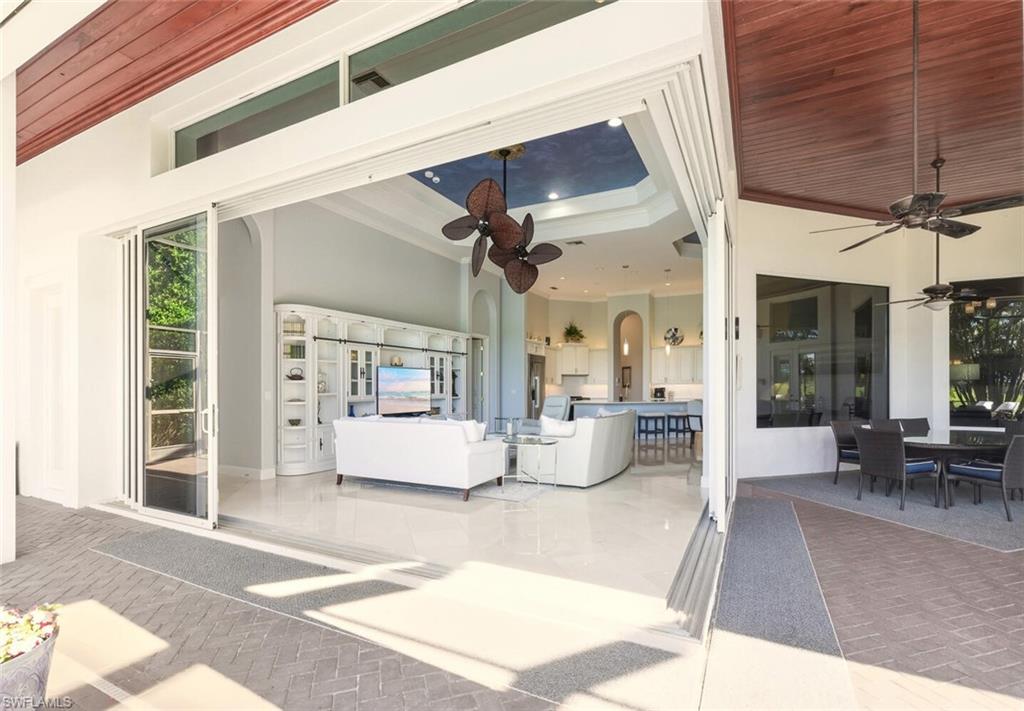 396 Terracina Way Naples, FL 34119 - Photo 26 of 50 Living room with a ceiling fan, wooden ceiling, a tray ceiling, arched walkways, and crown molding