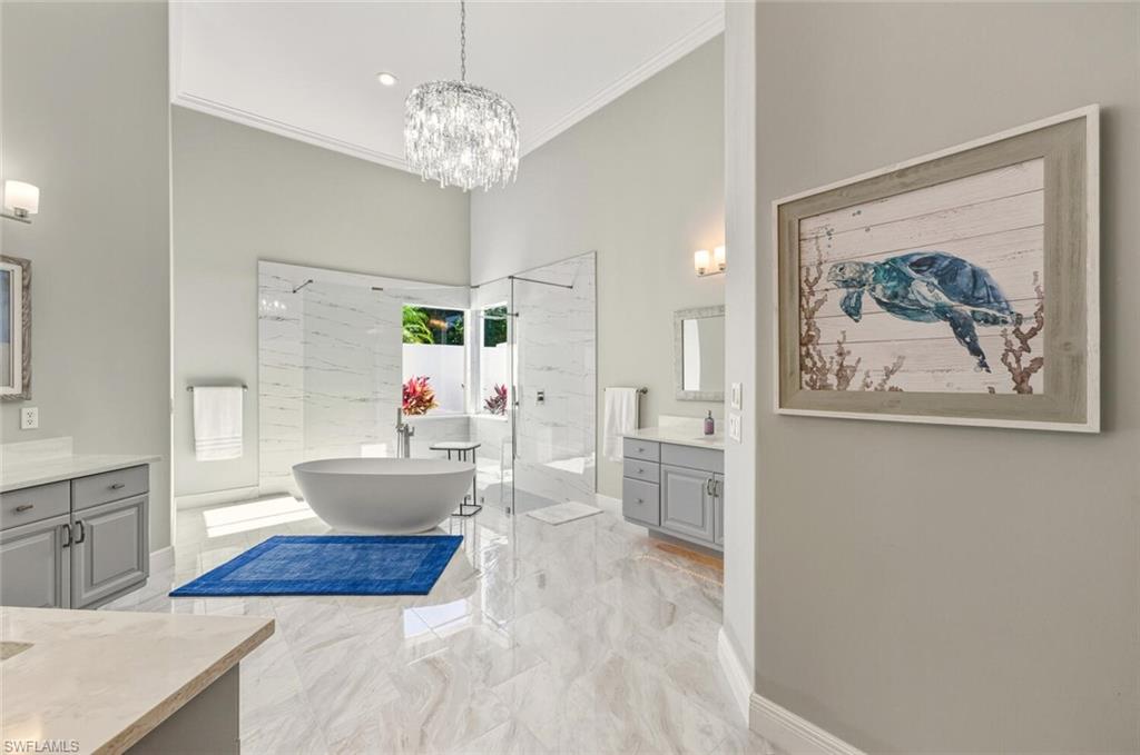 396 Terracina Way Naples, FL 34119 - Photo 36 of 50 Bathroom with two vanities, a marble finish shower, a freestanding bath, crown molding, and light marble finish flooring