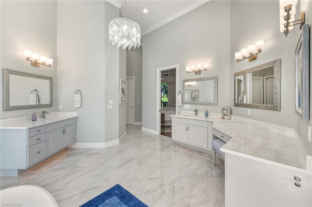 396 Terracina Way Naples, FL 34119 - Photo 38 of 50 Full bathroom featuring two vanities, light marble finish flooring, a high ceiling, crown molding, and a chandelier