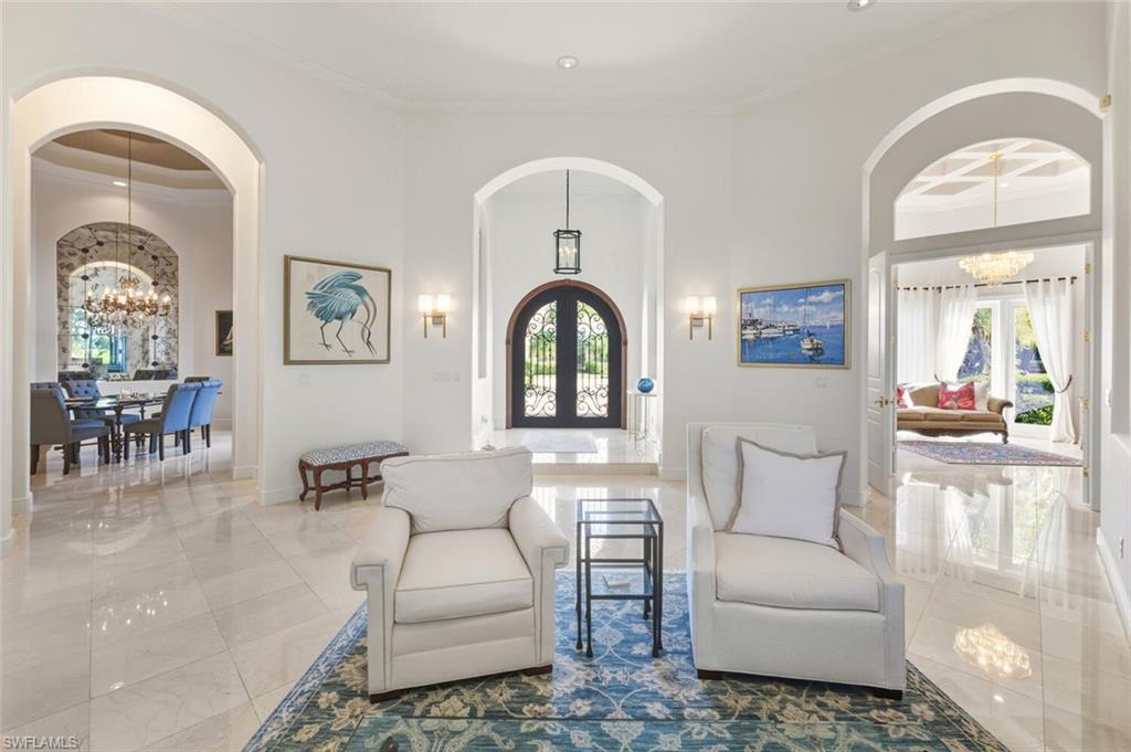 396 Terracina Way Naples, FL 34119 - Photo 4 of 50 Foyer featuring a chandelier, arched walkways, ornamental molding, a towering ceiling, and french doors