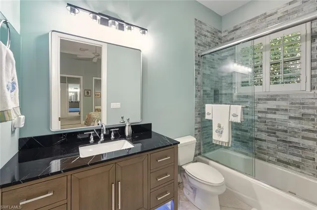 a bathroom with a granite countertop sink toilet and mirror