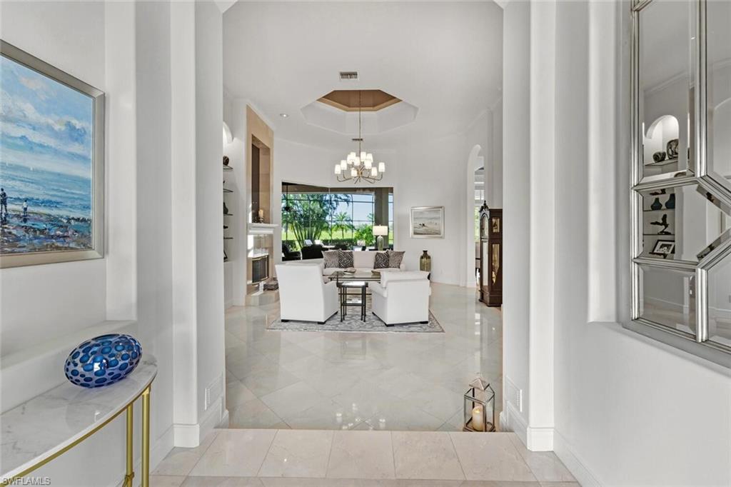 396 Terracina Way Naples, FL 34119 - Photo 5 of 50 Hall with a tray ceiling, arched walkways, and a chandelier