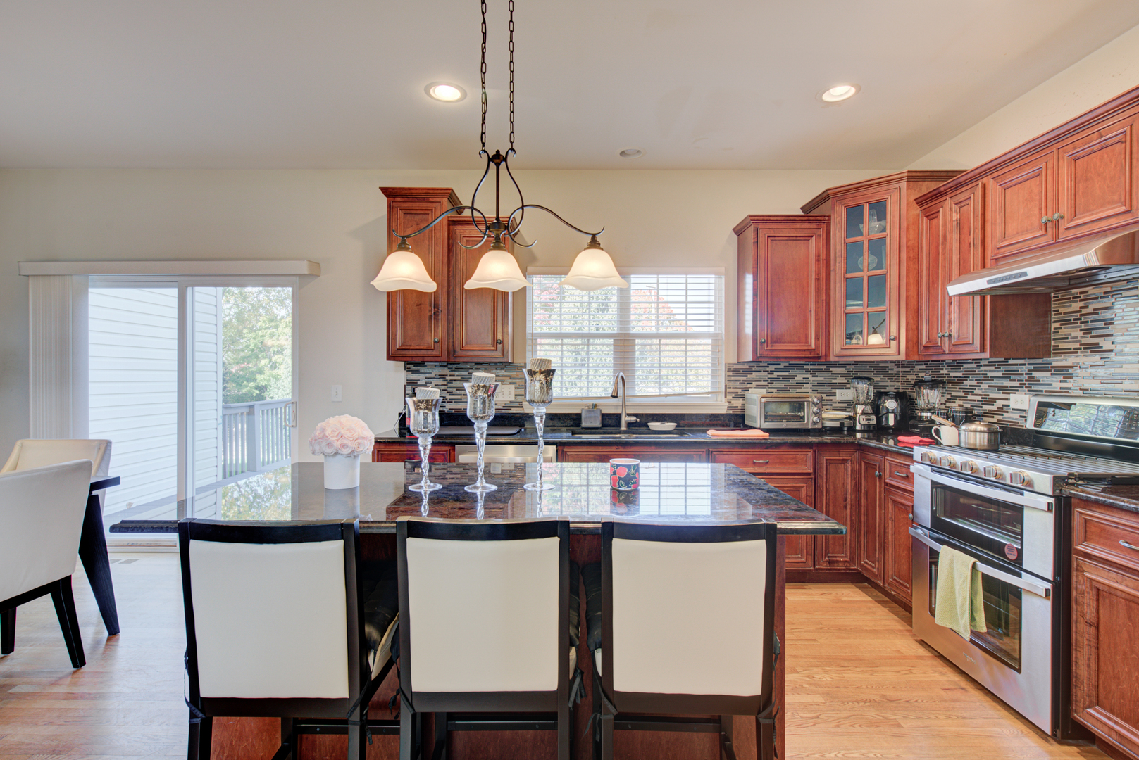 24520 Rockefeller Court Plainfield, IL 60544 - Photo 12 of 57 a kitchen with stainless steel appliances granite countertop a stove a sink dishwasher a dining table and chairs with wooden floor