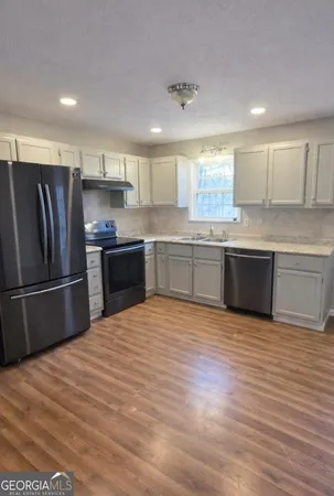 a large kitchen with stainless steel appliances granite countertop a sink and cabinets