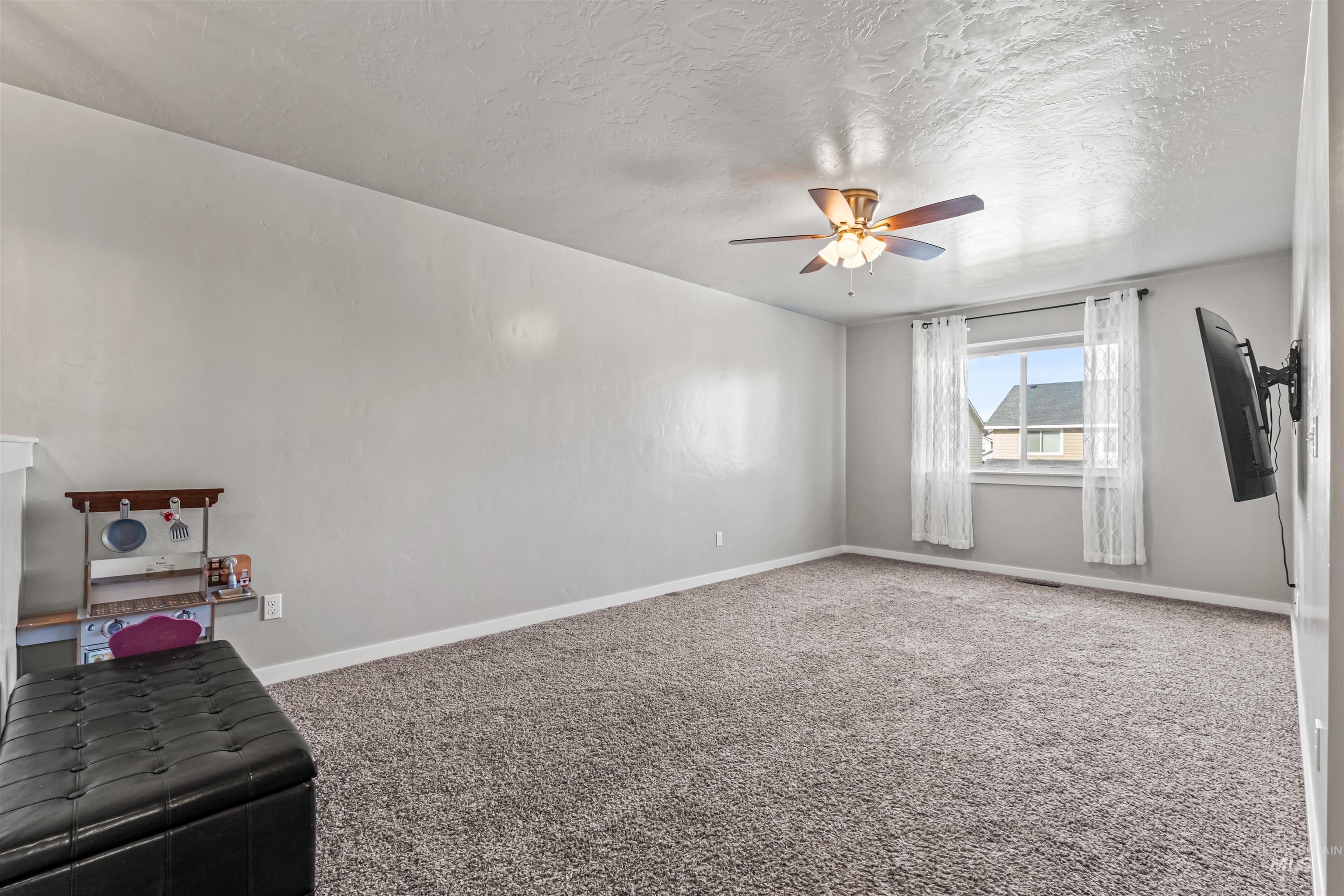 12030 West Abram Street Boise, ID 83713 - Photo 18 of 26 Carpeted empty room featuring a textured ceiling and a ceiling fan