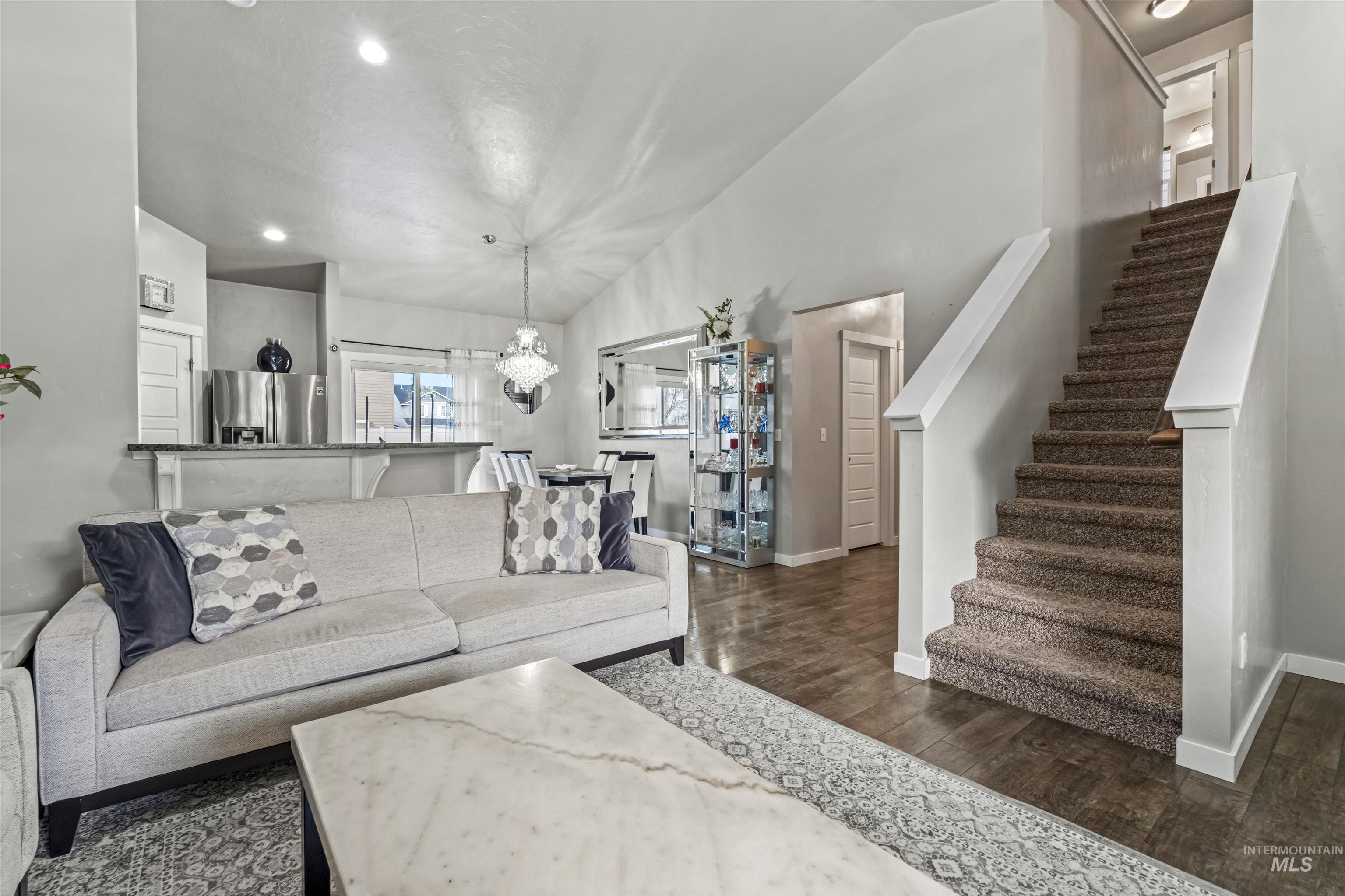 12030 West Abram Street Boise, ID 83713 - Photo 6 of 26 Living room featuring a chandelier, dark wood-style floors, and vaulted ceiling