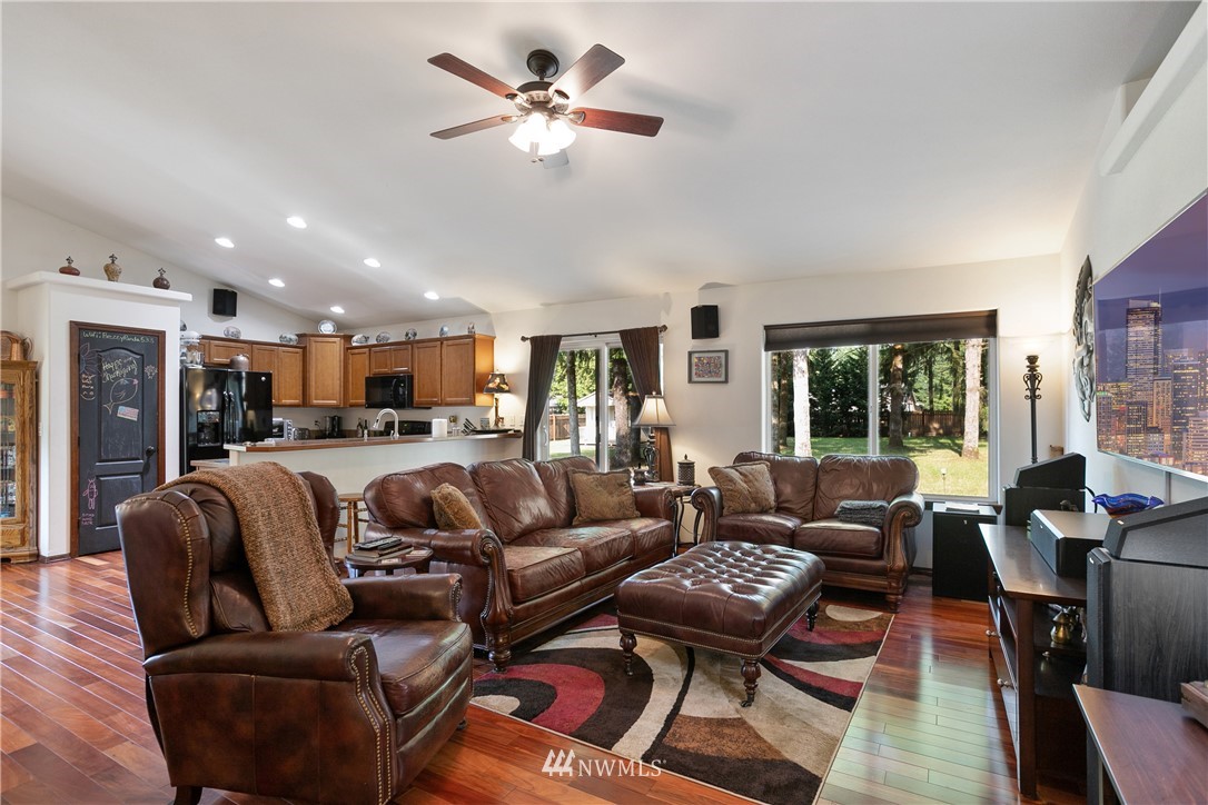 5129 180th Trail Southwest Rochester, WA 98579 - Photo 4 of 22 a living room with furniture a ceiling fan a fireplace and a large window