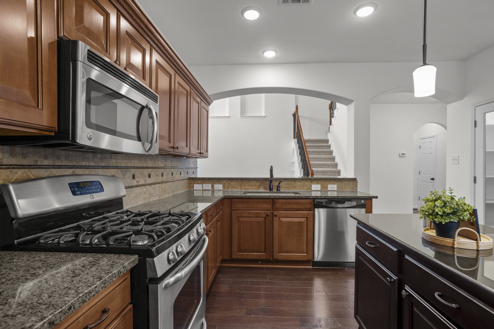 245 Razzmatazz Trail Buda, TX 78610 - Photo 12 of 37 Kitchen featuring stainless steel appliances, wood-finish flooring, granite countertops, and recessed lighting