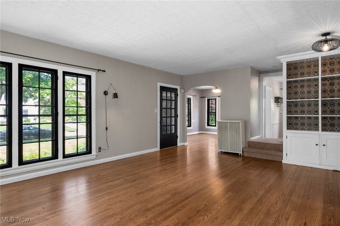 3677 Traver Road Shaker Heights, OH 44122 - Photo 6 of 35 Unfurnished living room featuring arched walkways, a textured ceiling, wood finished floors, and baseboards