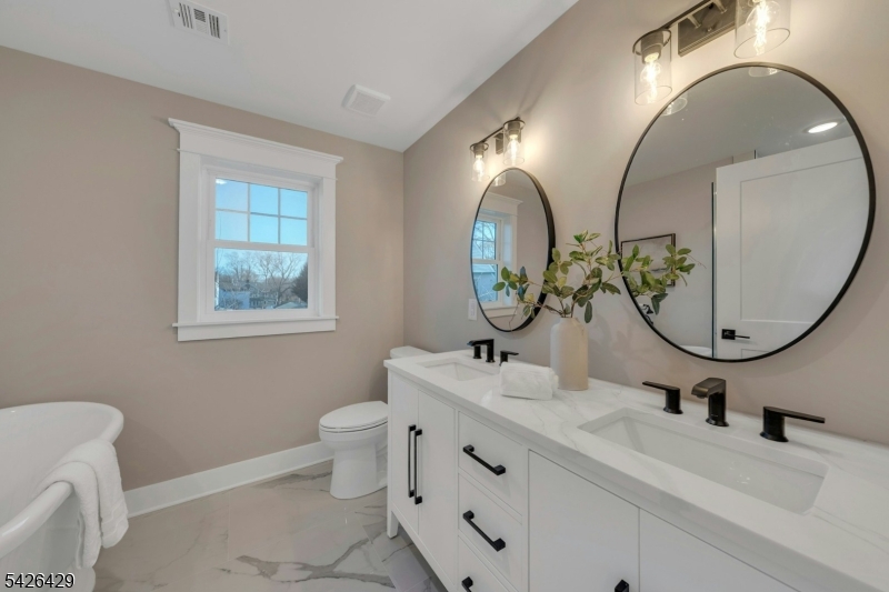 21 Spruce Street Cranford, NJ 07016 - Photo 21 of 40 a bathroom with a granite countertop toilet a sink and a mirror