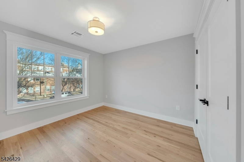 21 Spruce Street Cranford, NJ 07016 - Photo 26 of 40 a view of an empty room with wooden floor and a window