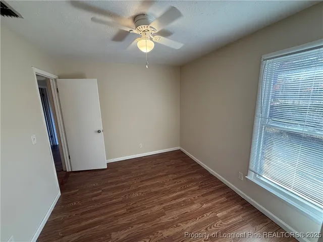an empty room with wooden floor and ceiling fan